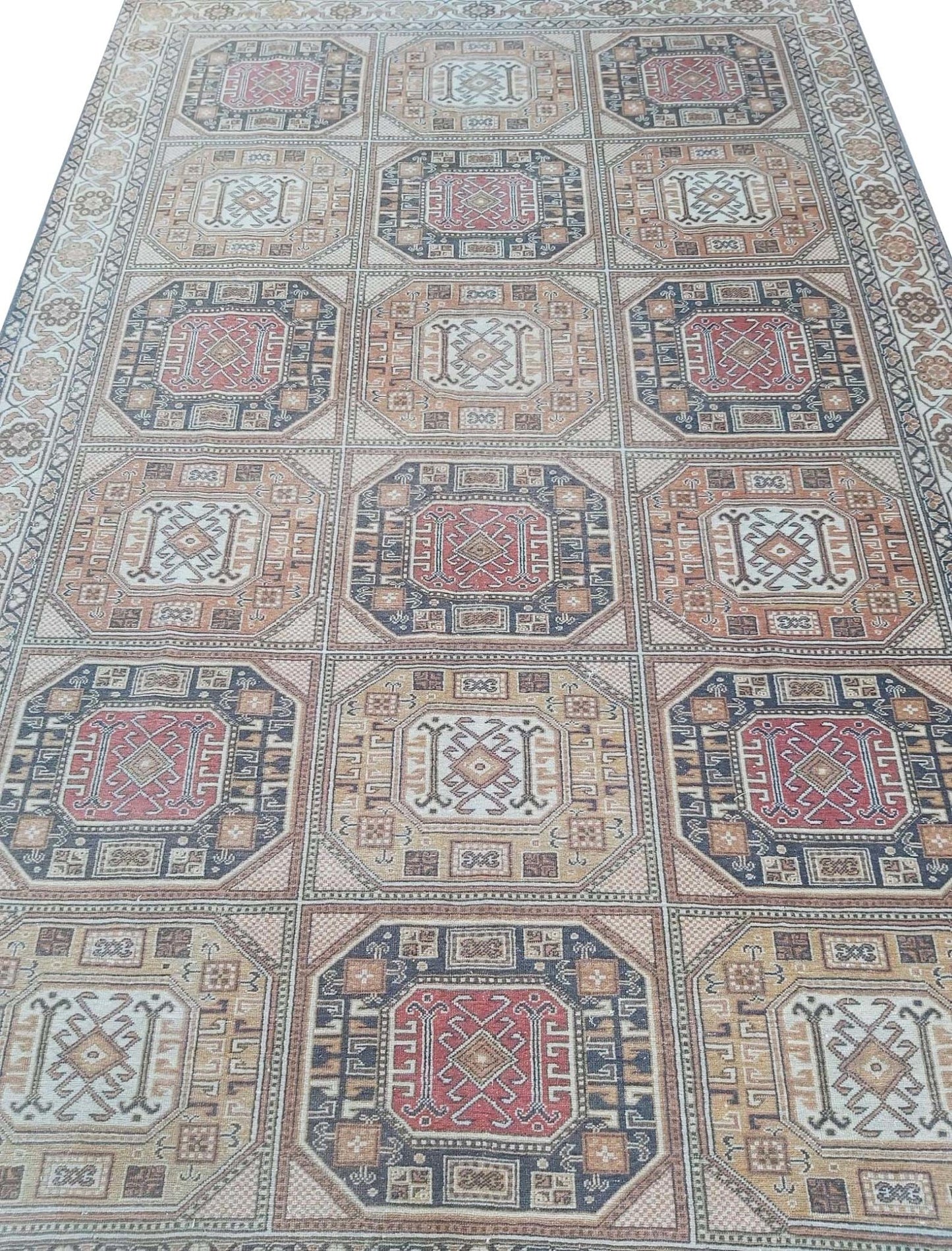 A vintage Turkish Oushak rug featuring a repeating geometric pattern in muted red and beige tones.
