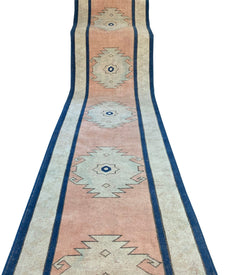 A vintage Turkish Oushak runner featuring tribal motifs in shades of pink, blue, and cream.