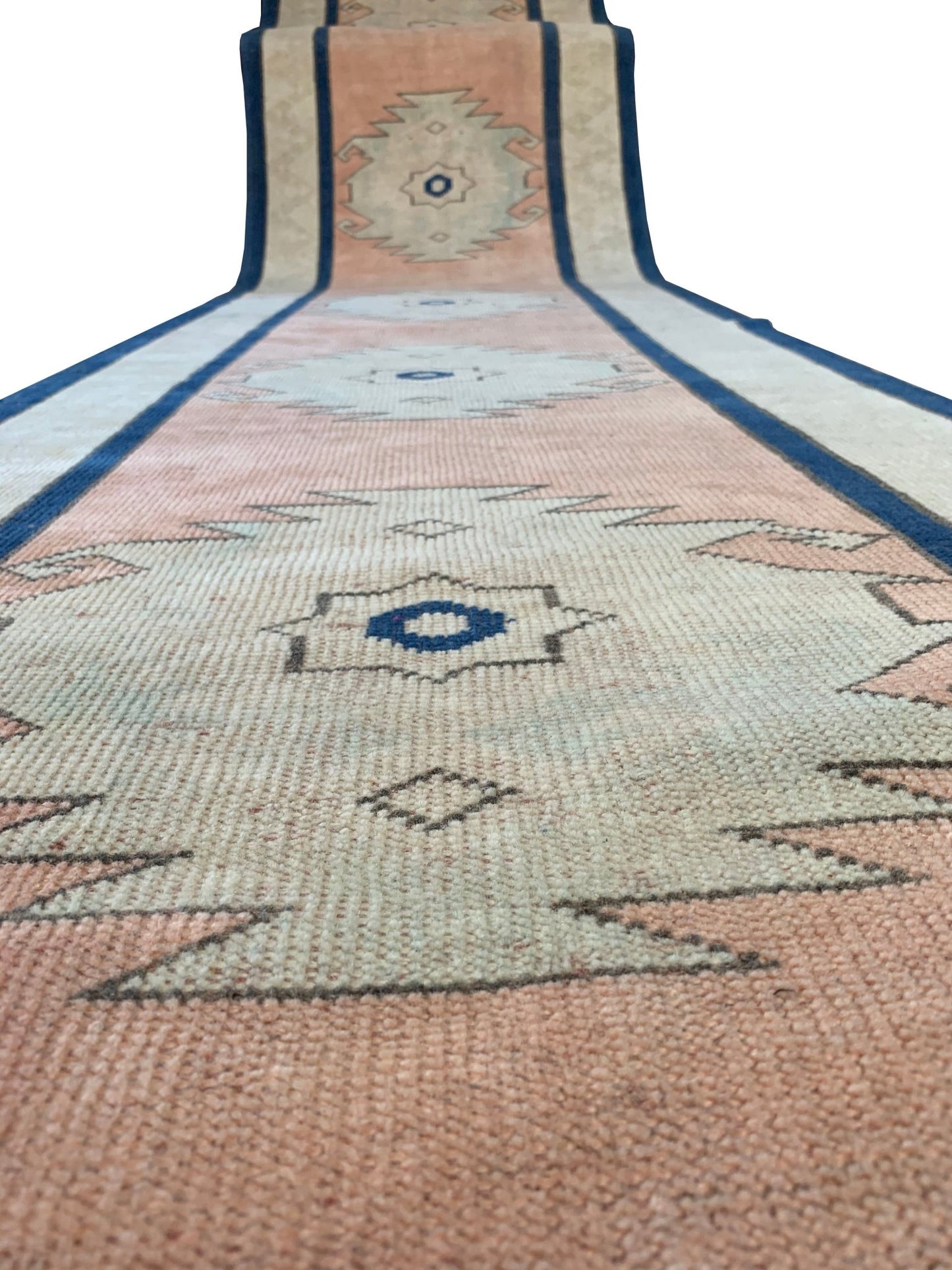 A vintage Turkish Oushak runner featuring tribal motifs in soft pink, cream, and blue tones.