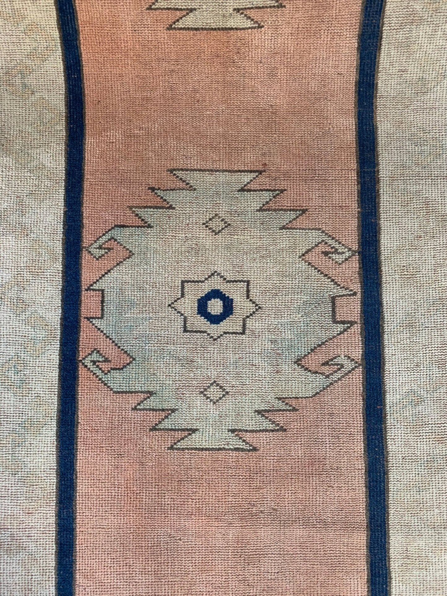 A vintage Turkish Oushak runner featuring a pale pink field with a central tribal medallion.
