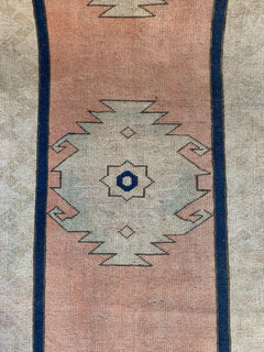 A vintage Turkish Oushak runner featuring a pale pink field with a central tribal medallion.