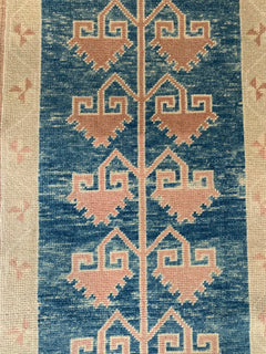 A vintage Turkish Oushak runner featuring a blue field with repeating pink tribal Seljuk motifs.