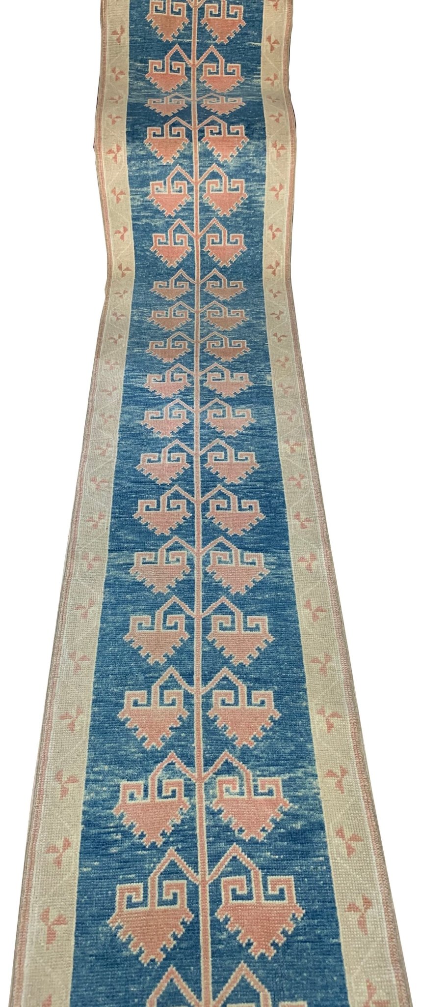 A vintage Turkish Oushak runner featuring a blue field with repeating pink tribal motifs.