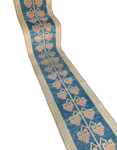 A vintage Turkish Oushak runner featuring a blue field with repeating pink tribal motifs.