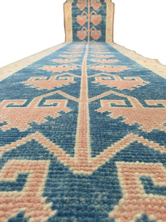 A vintage Turkish Oushak runner featuring pink tribal motifs on a blue wool background.