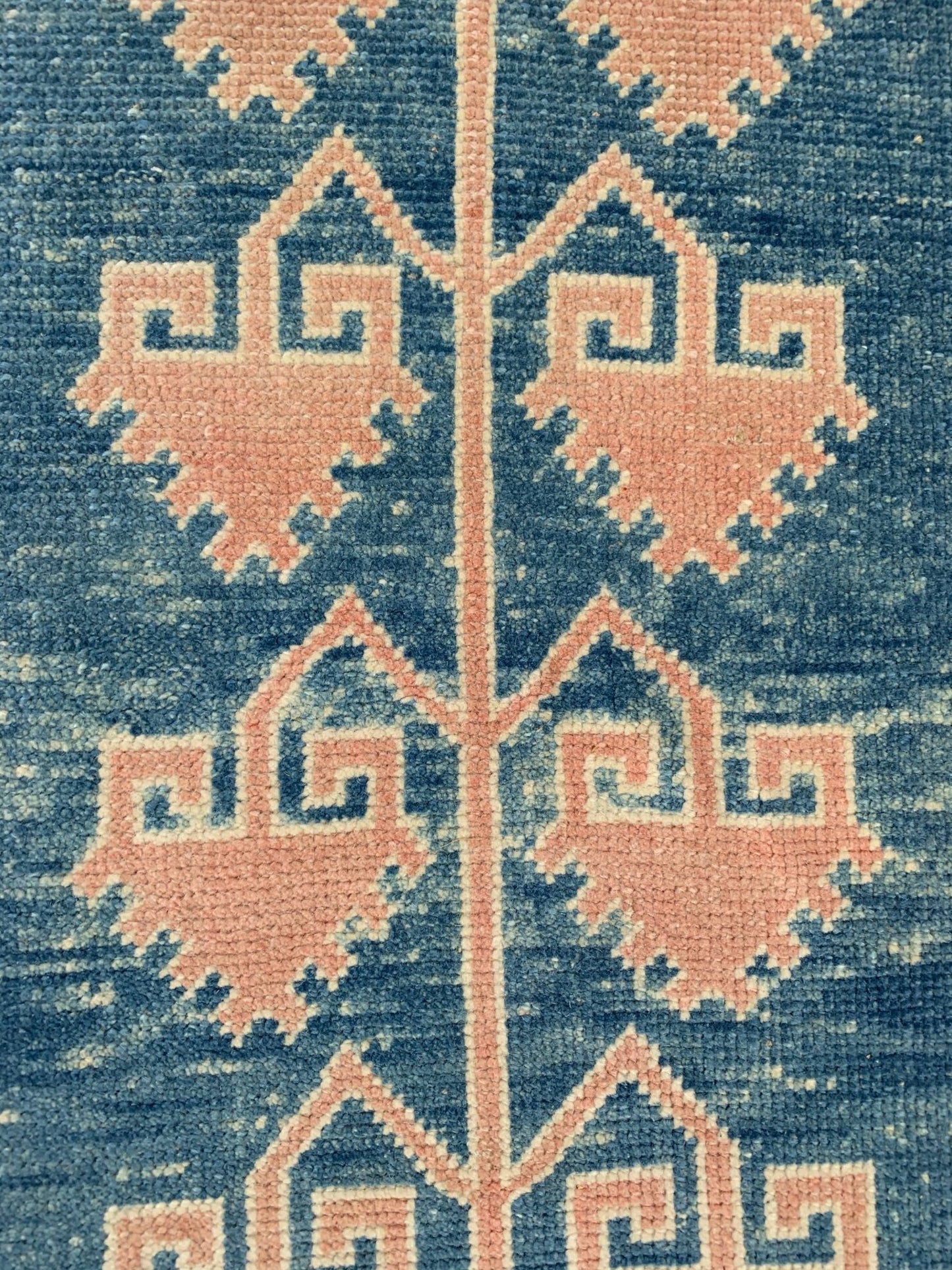 A vintage Turkish Oushak runner featuring pink geometric Seljuk motifs on a blue wool background.