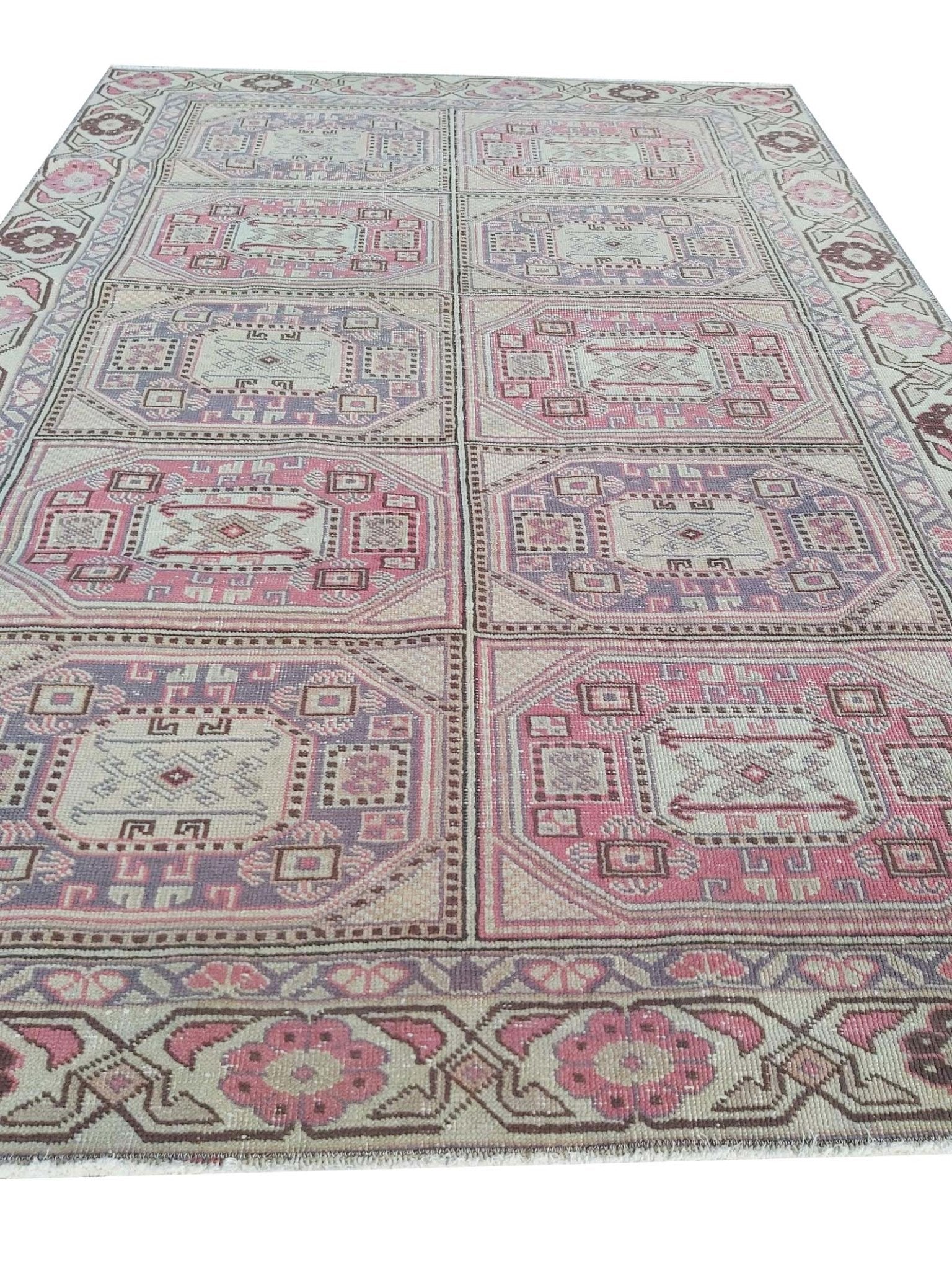 A vintage handmade Turkish wool rug featuring a geometric grid pattern in pink and purple tones.