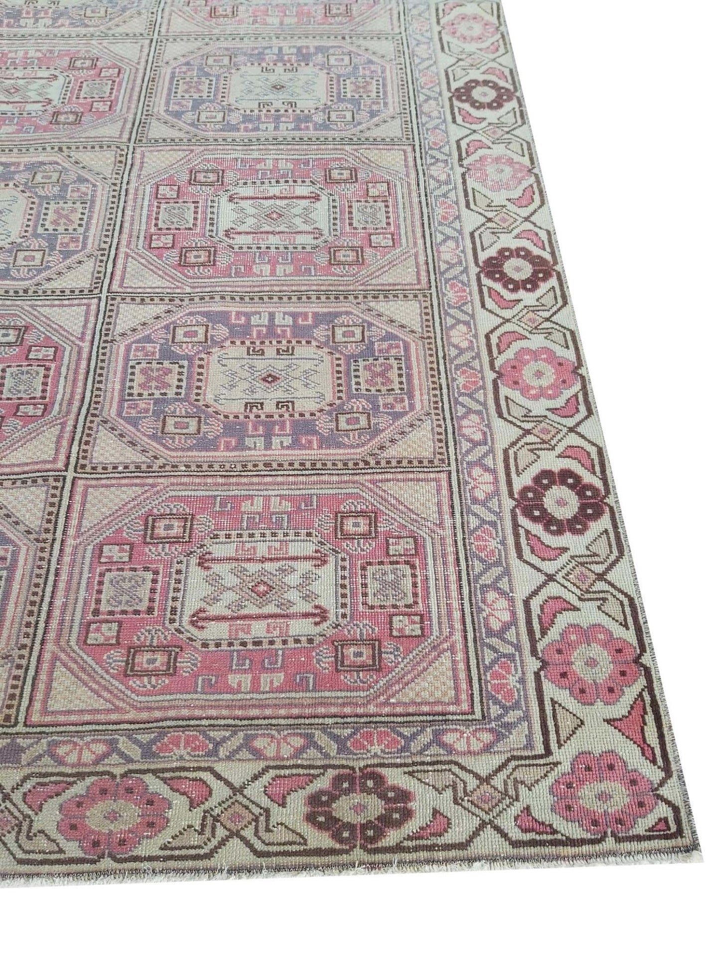 A vintage handmade Turkish wool rug featuring a geometric grid pattern in pink and purple tones.