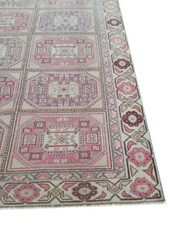 A vintage handmade Turkish wool rug featuring a geometric grid pattern in pink and purple tones.