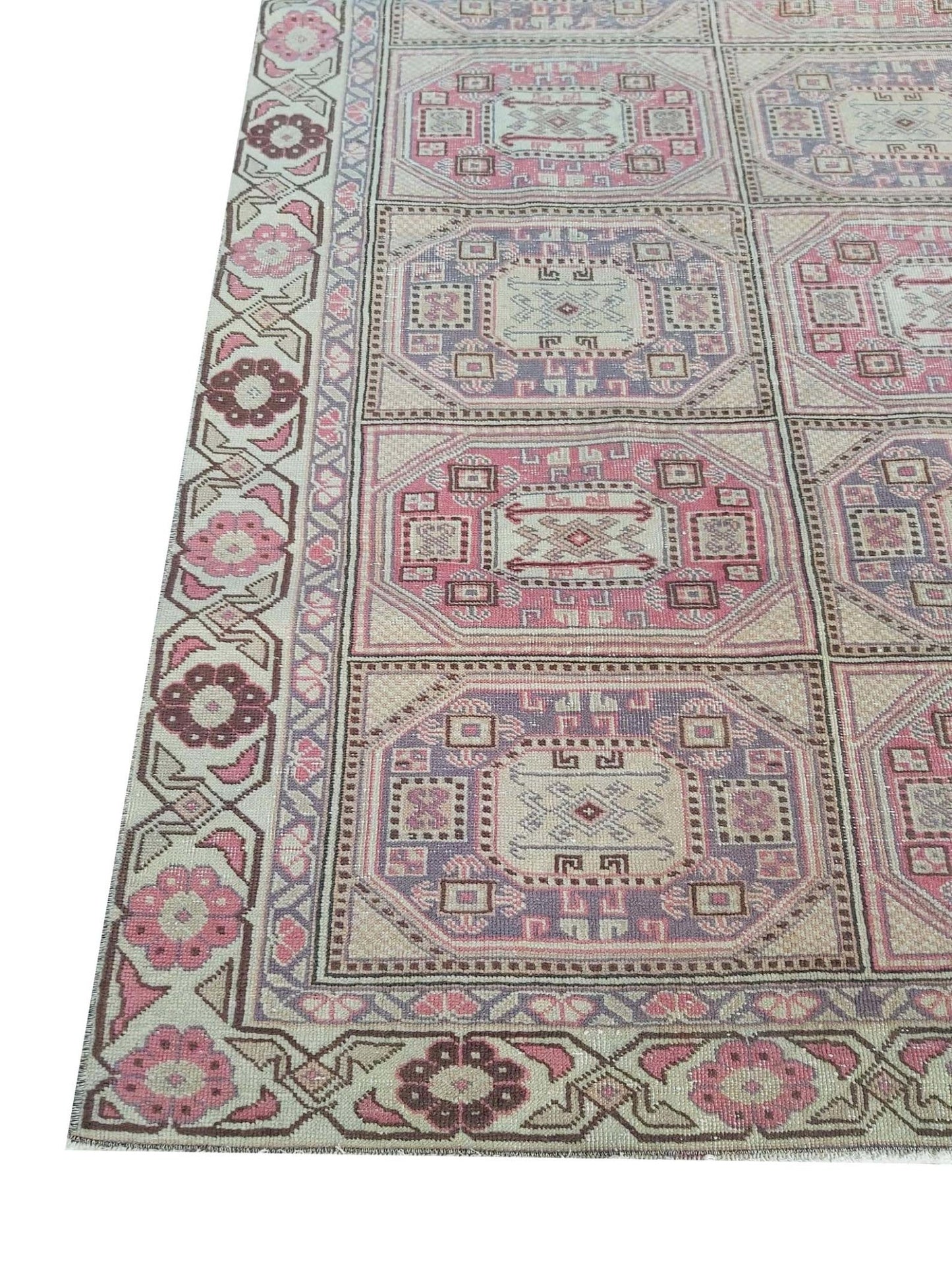 A vintage handmade Turkish wool rug featuring a geometric grid pattern in pink and purple tones.
