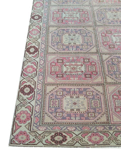 A vintage handmade Turkish wool rug featuring a geometric grid pattern in pink and purple tones.