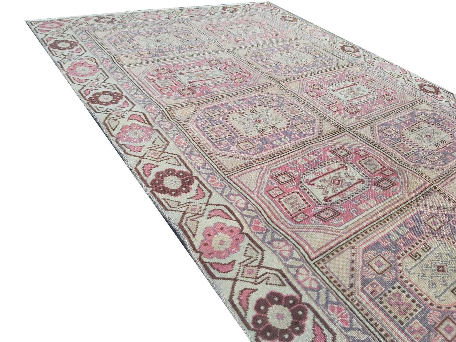 A vintage handmade Turkish wool rug featuring a geometric pattern in shades of pink and purple.