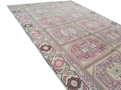 A vintage handmade Turkish wool rug featuring a geometric pattern in shades of pink and purple.