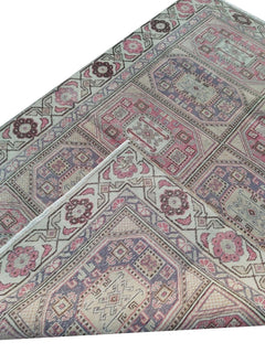 A vintage handmade Turkish wool rug featuring geometric patterns in pink, purple, and cream.