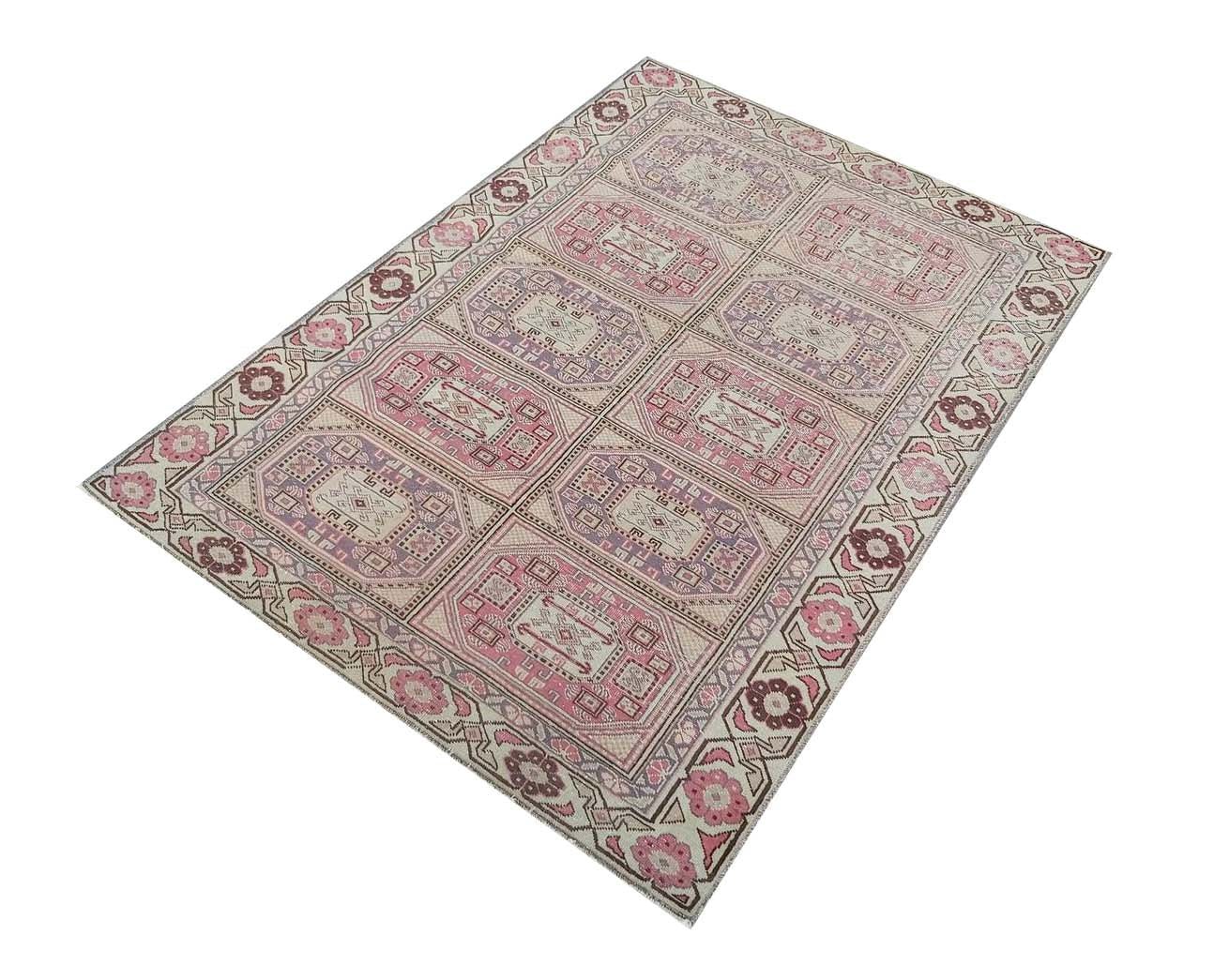 A vintage handmade Turkish wool rug featuring a geometric grid pattern in shades of pink and purple.
