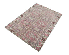 A vintage handmade Turkish wool rug featuring a geometric grid pattern in shades of pink and purple.