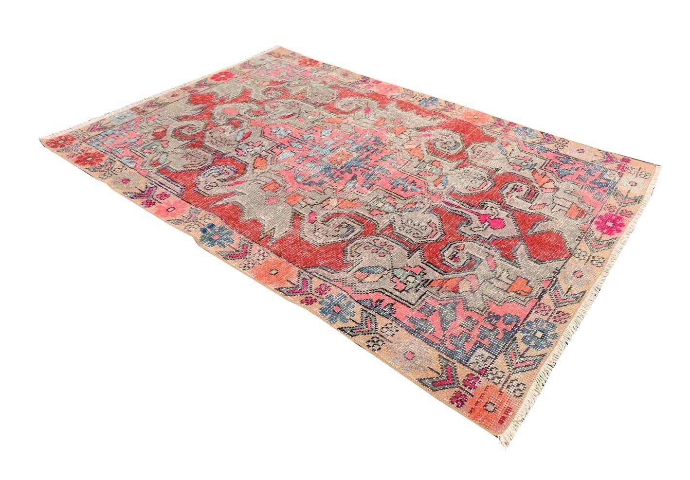 A vintage handmade Turkish wool rug featuring a distressed pattern in shades of red, grey, and blue.