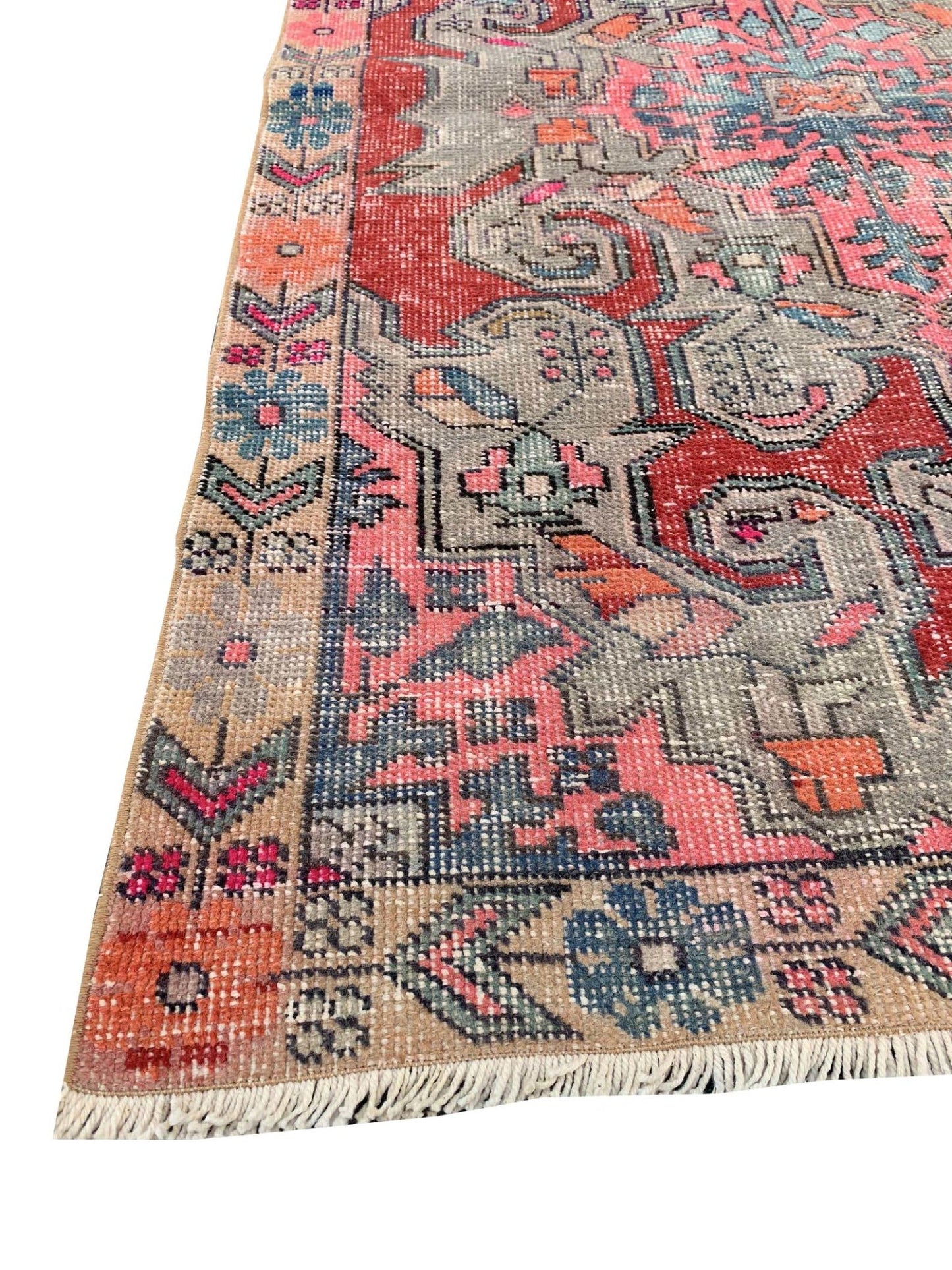 A vintage handmade Turkish wool rug featuring a colorful geometric pattern on a grey background.