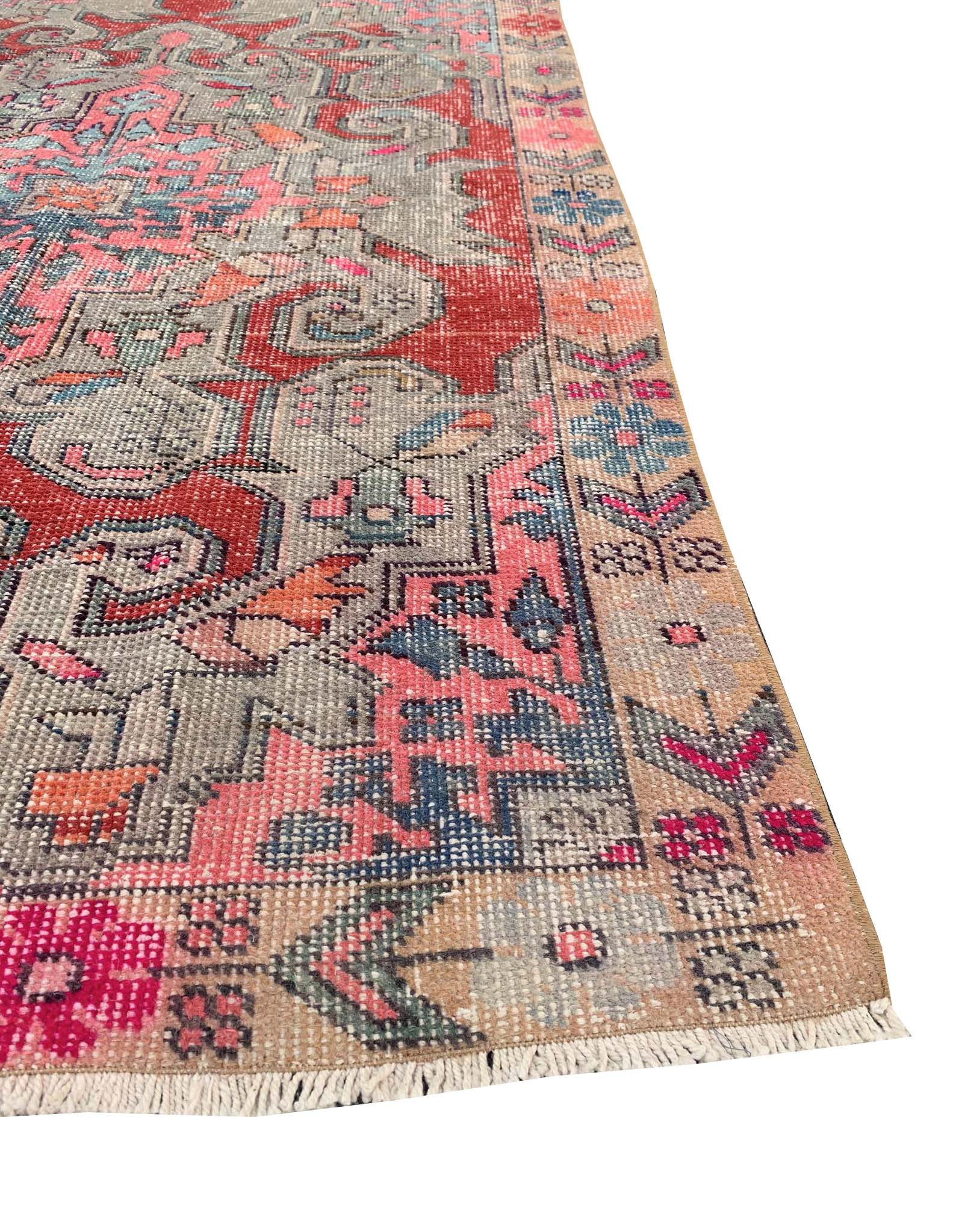 A handmade vintage Turkish wool rug featuring a geometric pattern in red, blue, and pink tones.