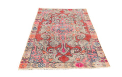 A vintage handmade Turkish wool rug featuring a distressed red, pink, and grey geometric pattern.