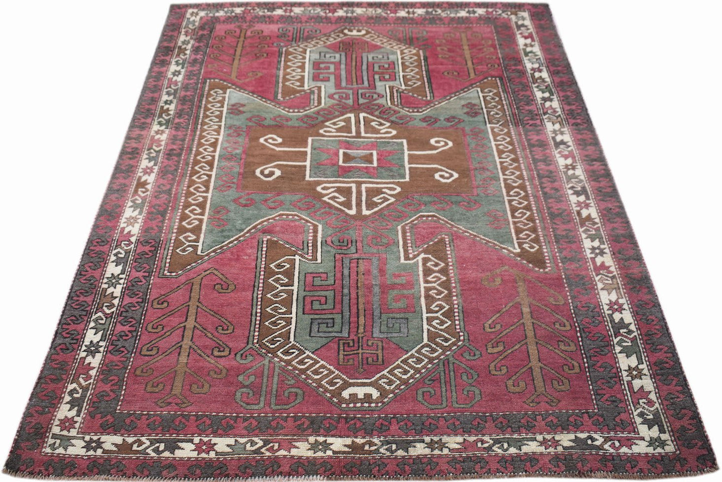 A vintage handwoven Iranian rug featuring geometric patterns in shades of pink, green, and brown.