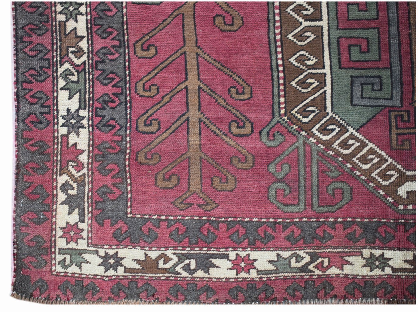 A vintage handwoven rug featuring a geometric tree motif in shades of pink, green, and brown.
