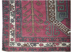 A vintage handwoven rug featuring a geometric tree motif in shades of pink, green, and brown.