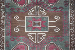 A vintage handwoven Turkish rug featuring a geometric brown, green, and red pattern.