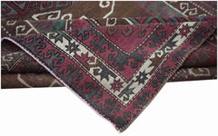 A handwoven vintage Turkish rug featuring geometric patterns in shades of red, brown, and green.