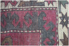A close-up view of a handwoven vintage Turkish rug featuring geometric patterns in red and brown.