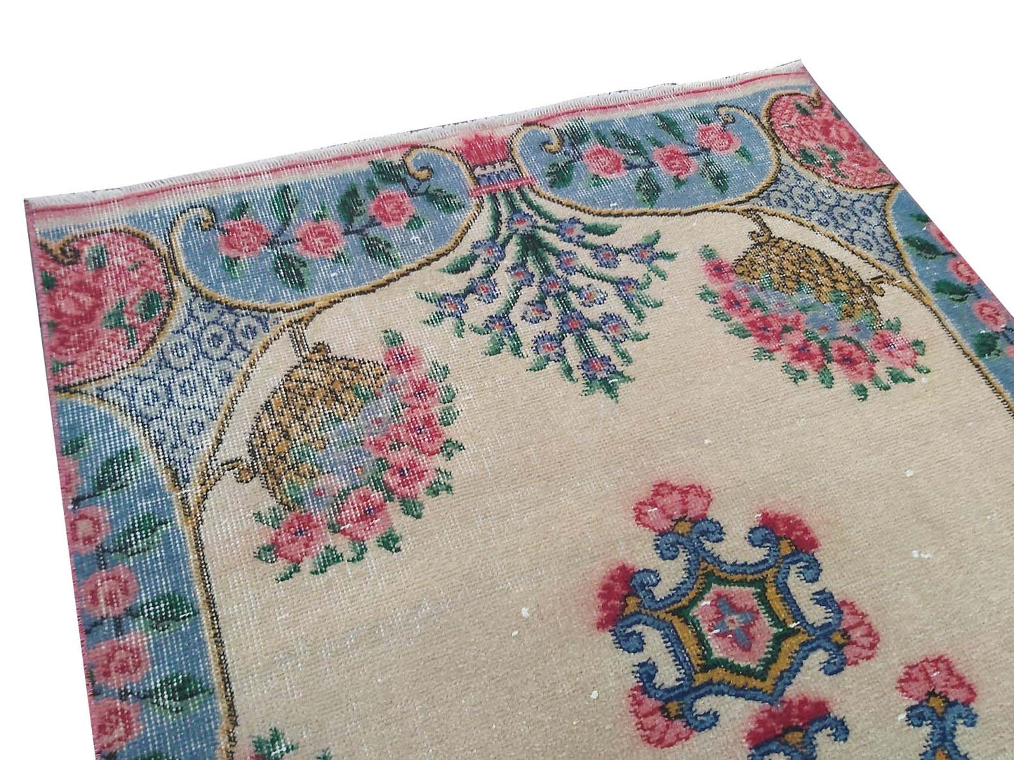 A vintage handmade Turkish wool rug featuring a floral pattern on a cream background.