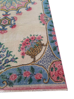 A vintage Turkish rug featuring a floral basket motif on a cream field with a blue border.