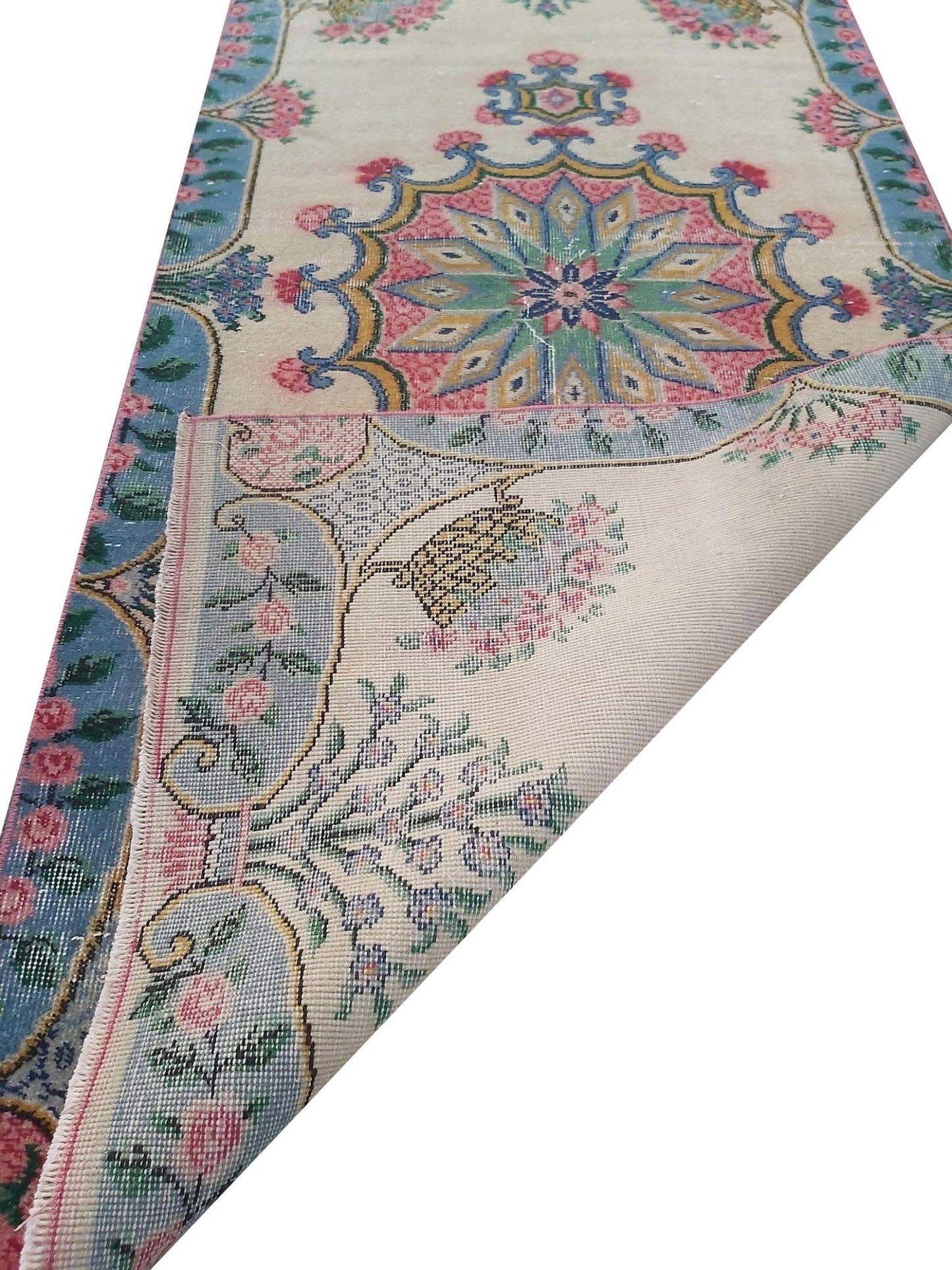 A vintage handmade Turkish wool runner featuring a floral medallion pattern in blue and pink.