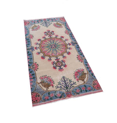A vintage handmade Turkish wool rug featuring a central floral medallion on a cream background.