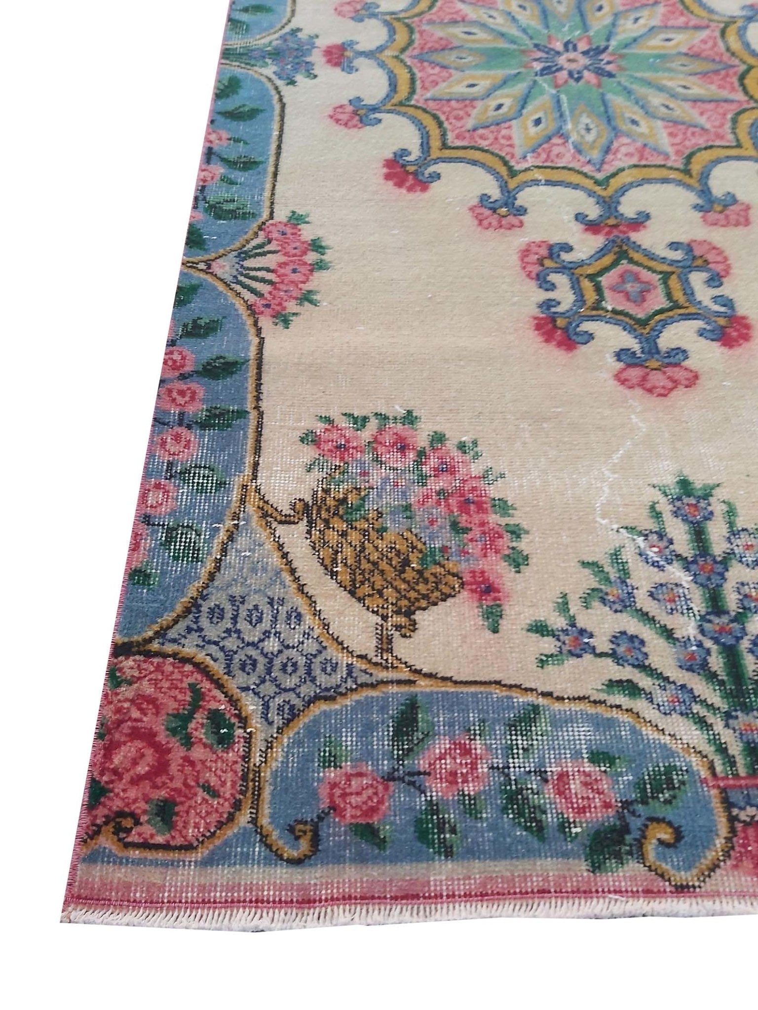 A vintage handmade Turkish wool rug featuring a floral pattern with a blue border and cream field.