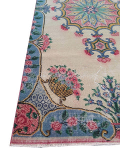 A vintage handmade Turkish wool rug featuring a floral pattern with a blue border and cream field.