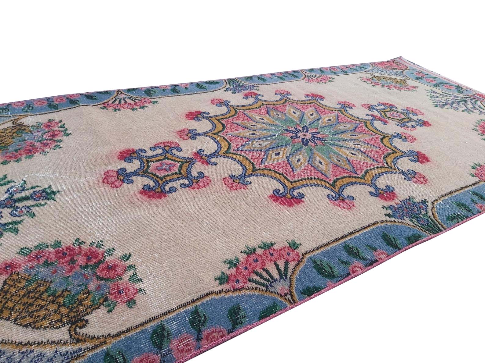 A vintage handmade Turkish wool rug featuring a central floral medallion on a beige field.