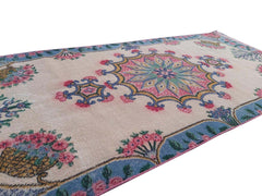 A vintage handmade Turkish wool rug featuring a central floral medallion on a beige field.