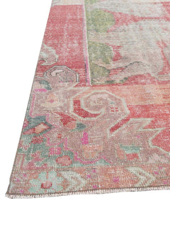 A vintage handmade Turkish rug featuring a faded floral pattern in shades of pink and green.