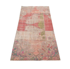 A vintage handmade Turkish wool rug featuring a faded geometric pattern in shades of red and pink.
