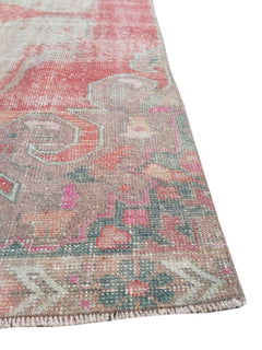 A vintage handmade Turkish wool rug featuring a faded geometric pattern in pink and muted green.
