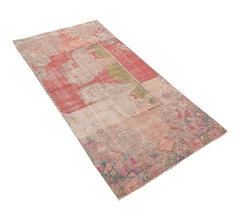 A rectangular vintage Turkish rug featuring a faded, distressed pattern in shades of red and pink.