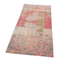 A vintage handmade Turkish wool rug featuring a faded geometric pattern in shades of red and green.