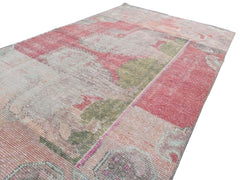 A vintage handmade Turkish wool rug featuring a distressed pattern in shades of pink and green.