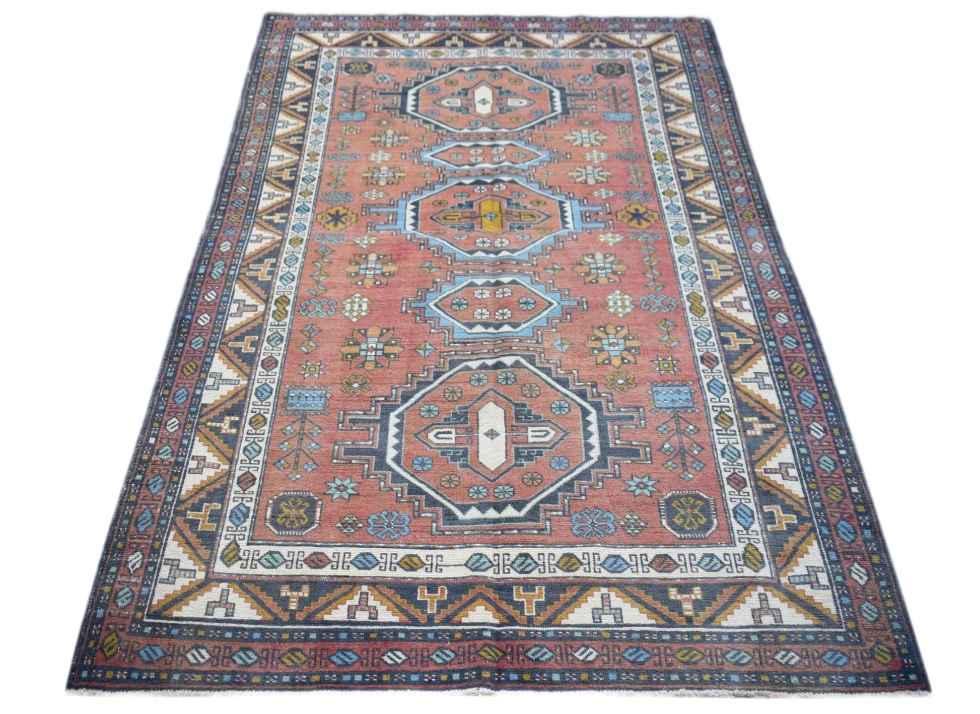A vintage handwoven Turkish rug featuring a geometric medallion pattern in shades of red and blue.