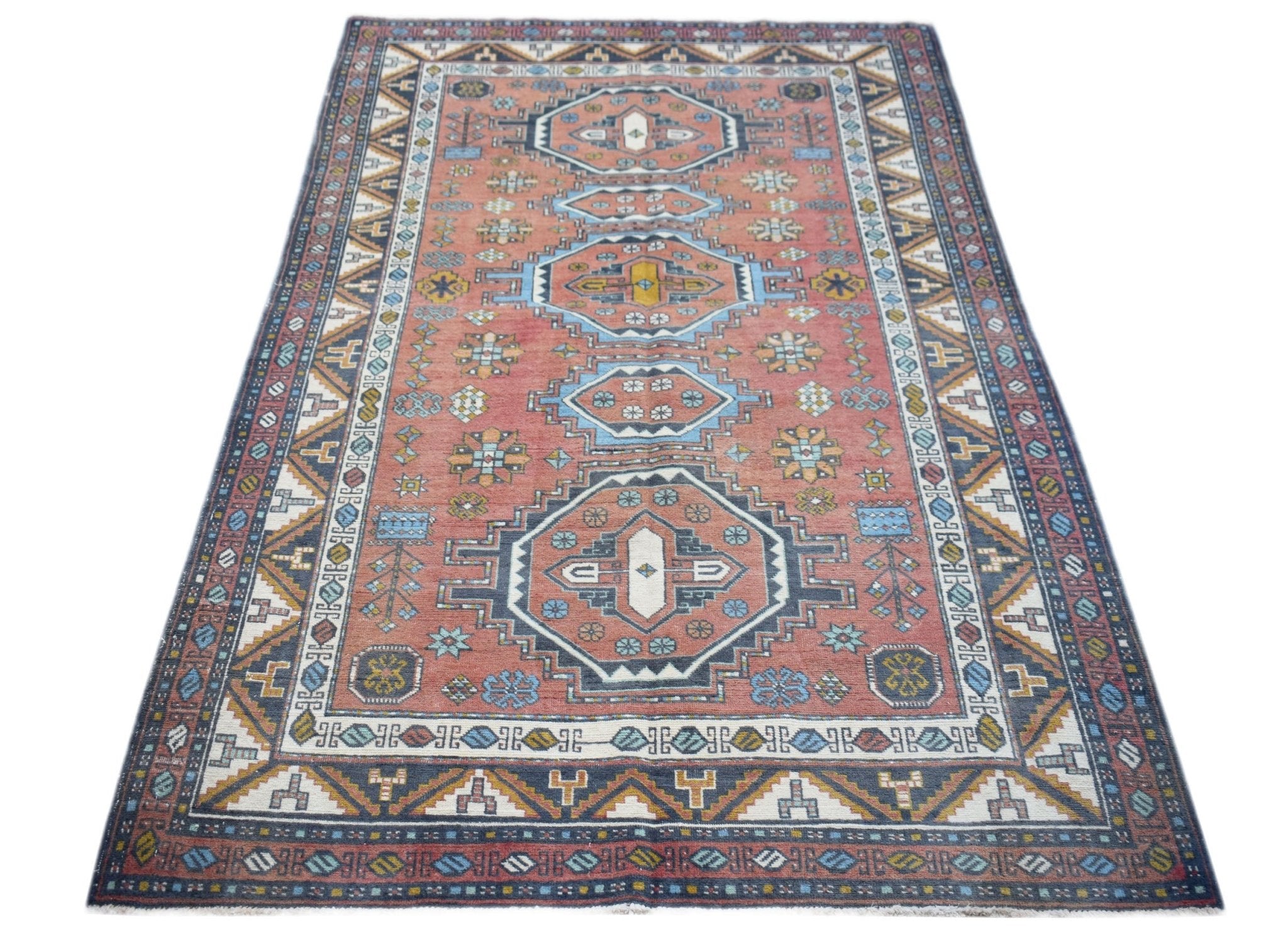 A vintage handwoven Turkish rug featuring a geometric medallion pattern in shades of red and blue.
