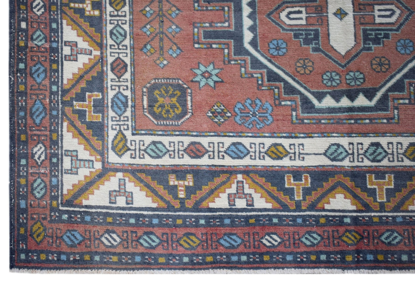 A vintage handwoven Turkish wool rug featuring geometric patterns in red, blue, and cream.