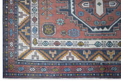 A vintage handwoven Turkish wool rug featuring geometric patterns in red, blue, and cream.