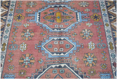 A vintage handwoven Turkish wool rug featuring geometric medallions in red, blue, and yellow.