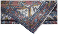 A vintage handwoven Turkish wool rug featuring geometric patterns in red, blue, and cream.